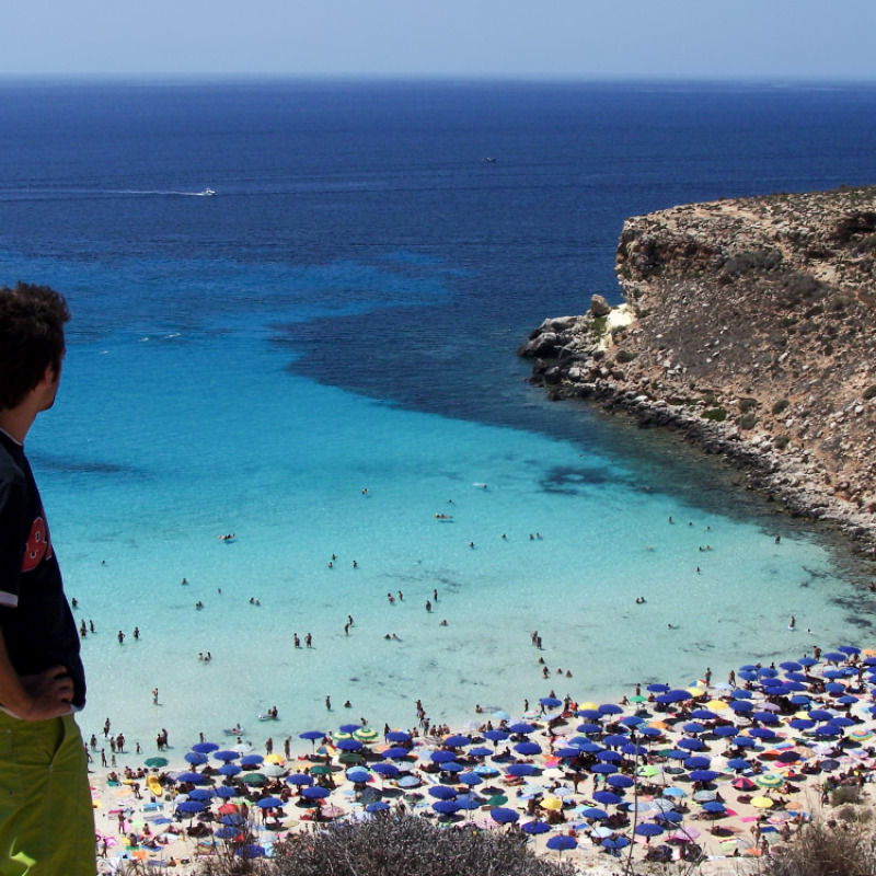 young tourist looks at the magnificent beach of rabbits in Lampedusa, Sicily, Italy