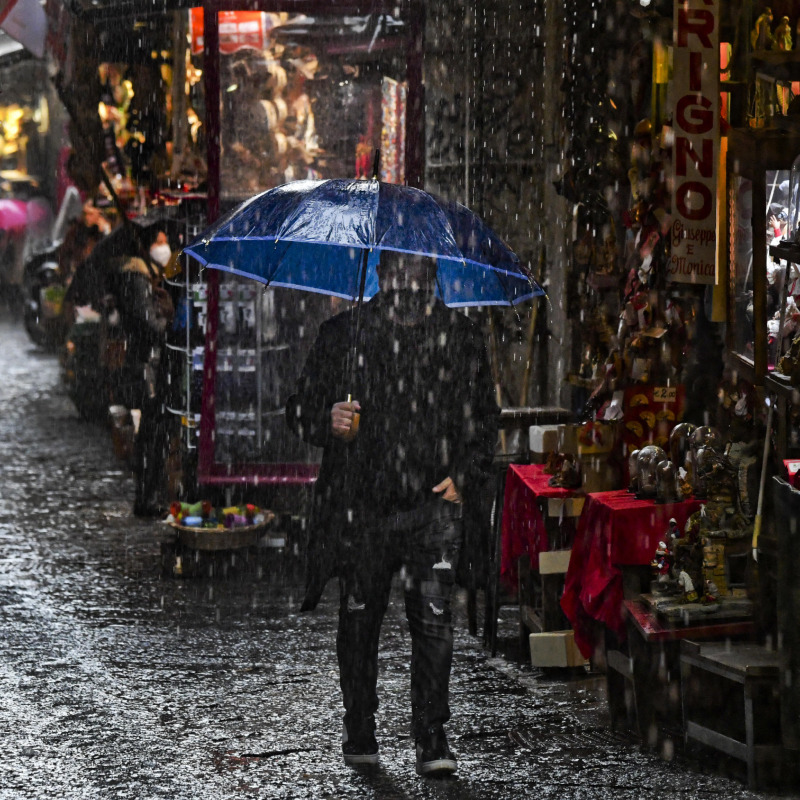Ombrelli riparano dalla pioggia i pochi visitatori di San Gregorio Armeno, strada del centro storico di Napoli che ospita le botteghe degli artigiani del presepe, 7 dicembre 2020.ANSA / CIRO FUSCO